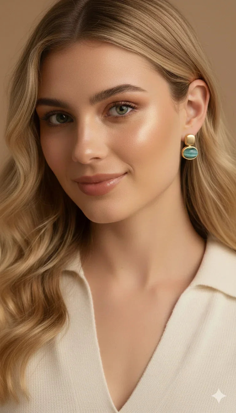 Donna con orecchino elegante dorato con pietra verde, look raffinato su sfondo beige